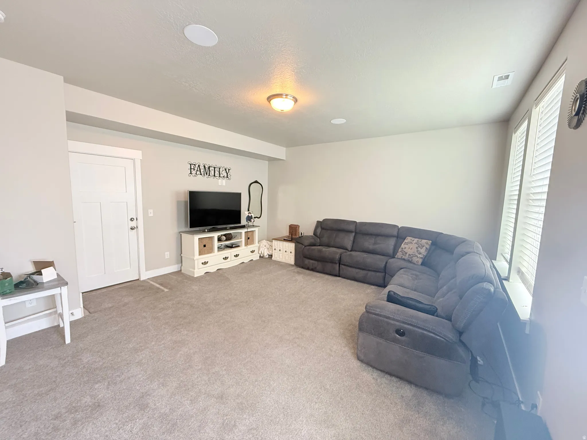 Recessed ceiling lighting, flush-mount ceiling light fixture, white interior door with paneling, window with white plantation shutters, and light-toned wall-to-wall carpeting
