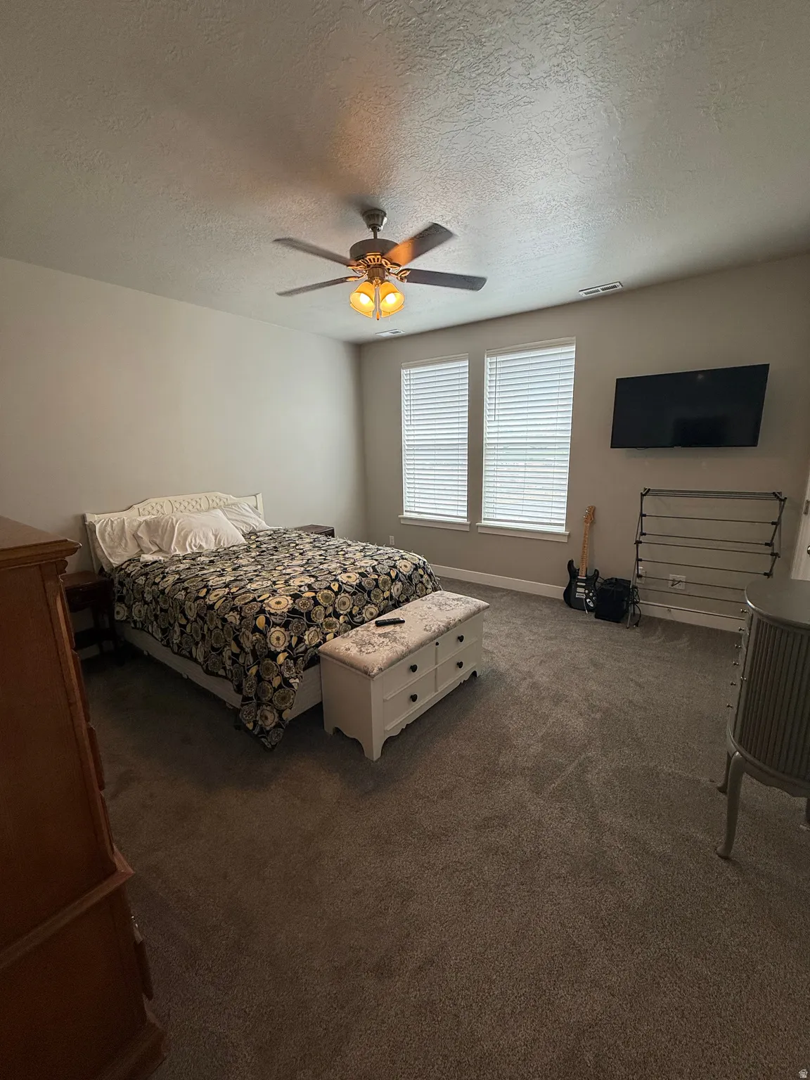 Carpeted flooring, dual windows with blinds, and a ceiling fan with integrated lighting