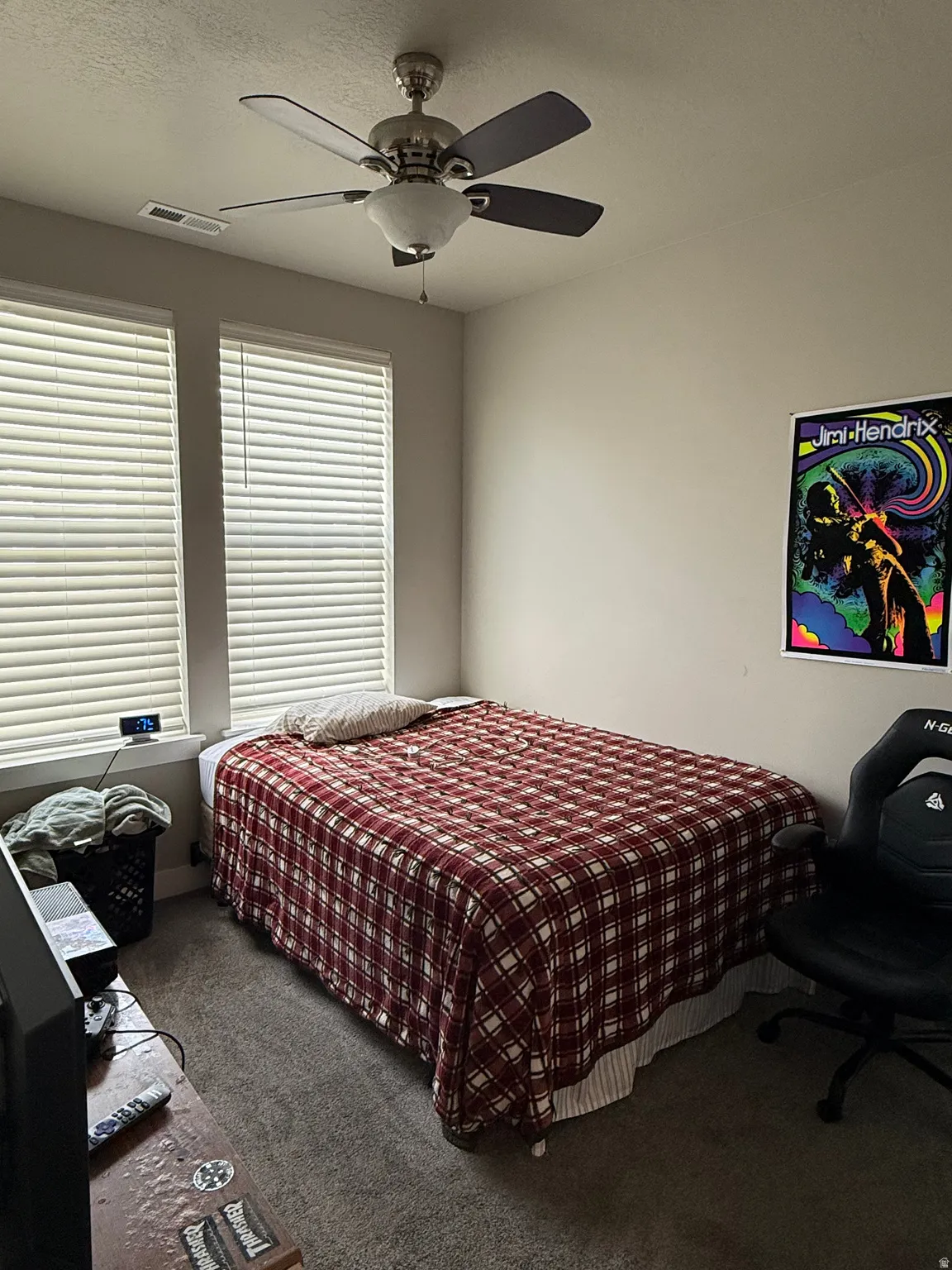 Neutral wall color, two windows with blinds, ceiling fan with integrated lighting, and carpeted flooring