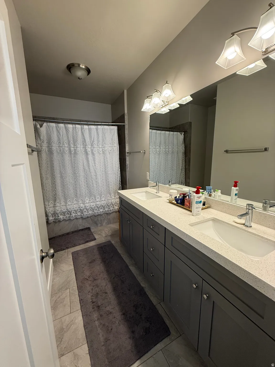 Dual vanity with integrated sinks, light-toned countertop, and gray wood-finish cabinetry