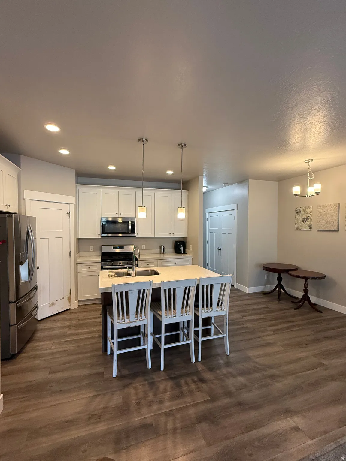 Kitchen featuring white cabinetry, stainless steel appliances, a center island with seating, and wood-finish flooring