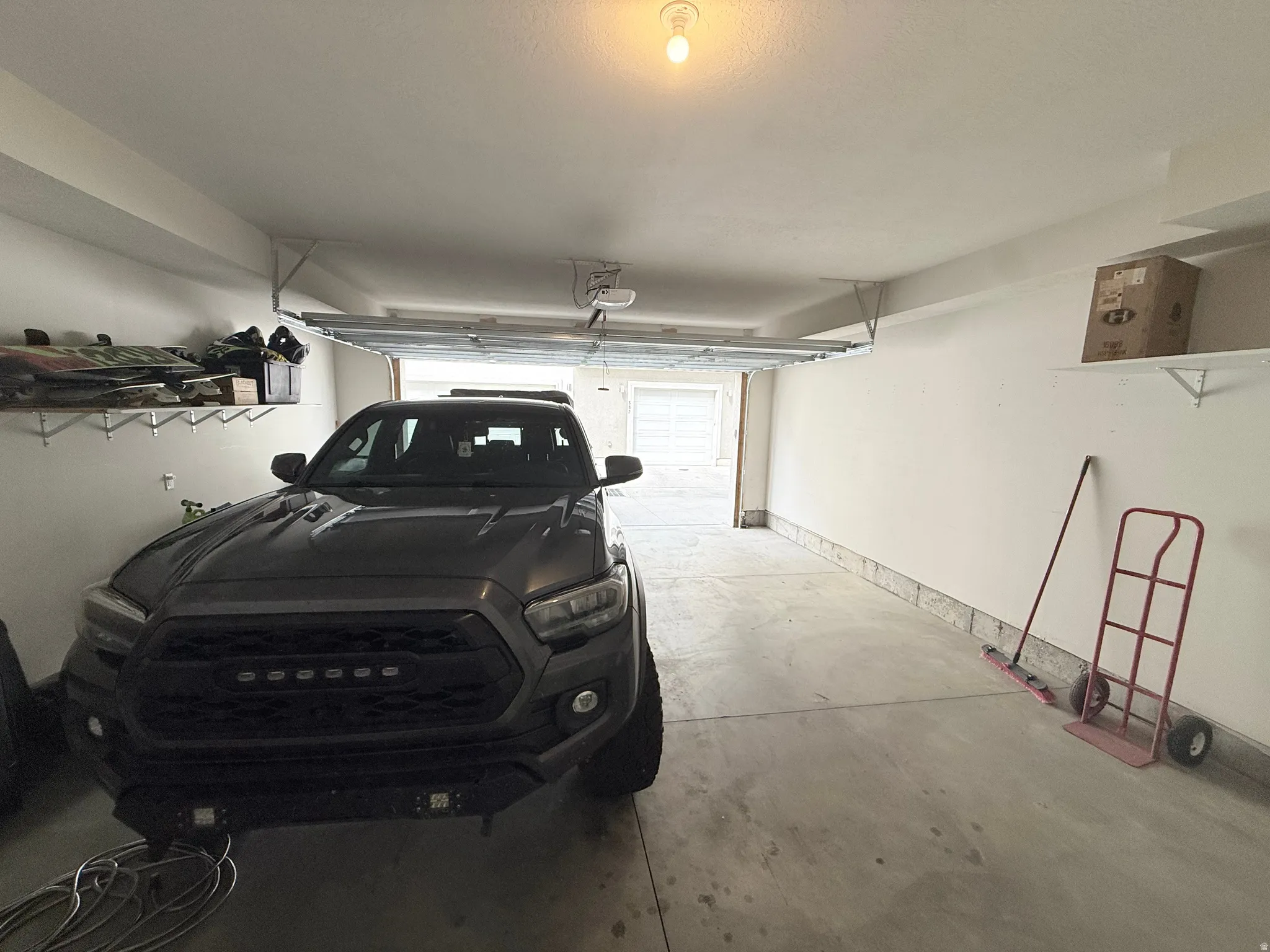 Attached shelving units, concrete flooring, and ceiling-mounted lighting