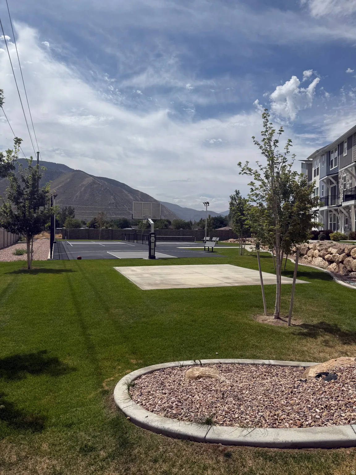 Expansive lawn area with a concrete pad and a multi-sport court