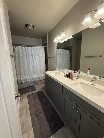 Dual vanity with integrated sinks, light-toned countertop, and gray wood-finish cabinetry