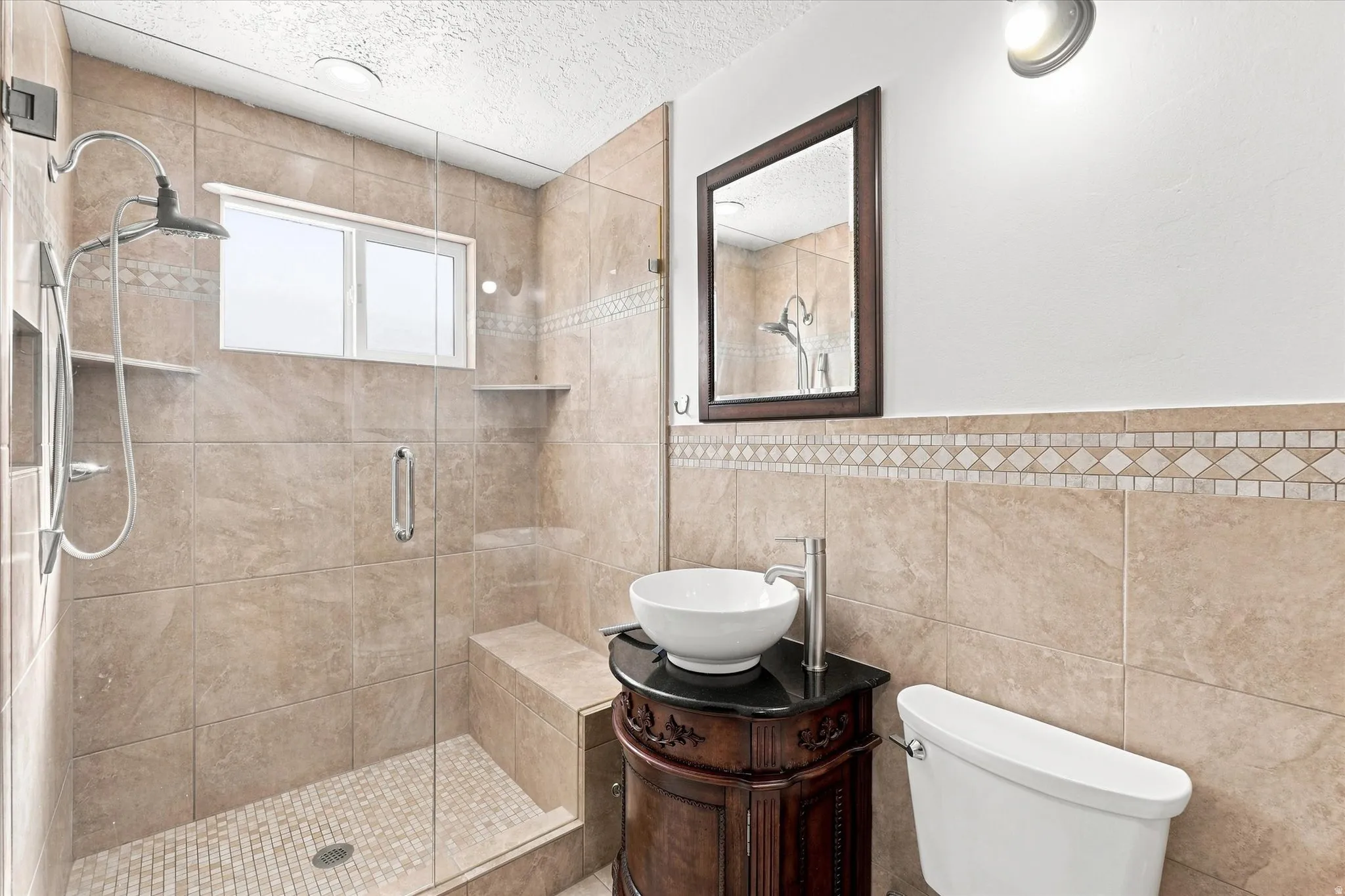 Tiled shower enclosure with a built-in bench, rain shower head, and an integrated niche