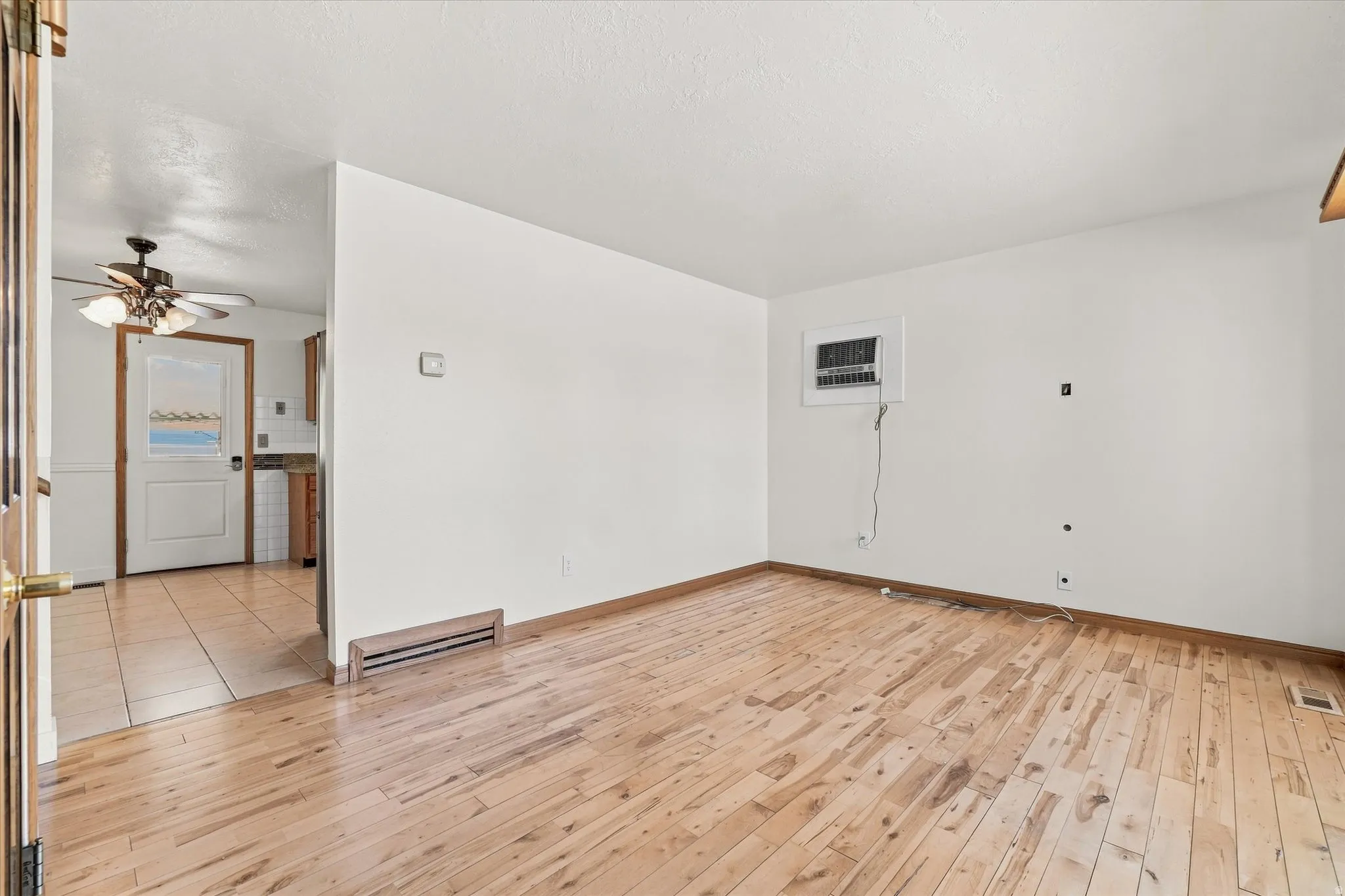 Wood-finish flooring throughout the main room, with a window-mounted air conditioning unit