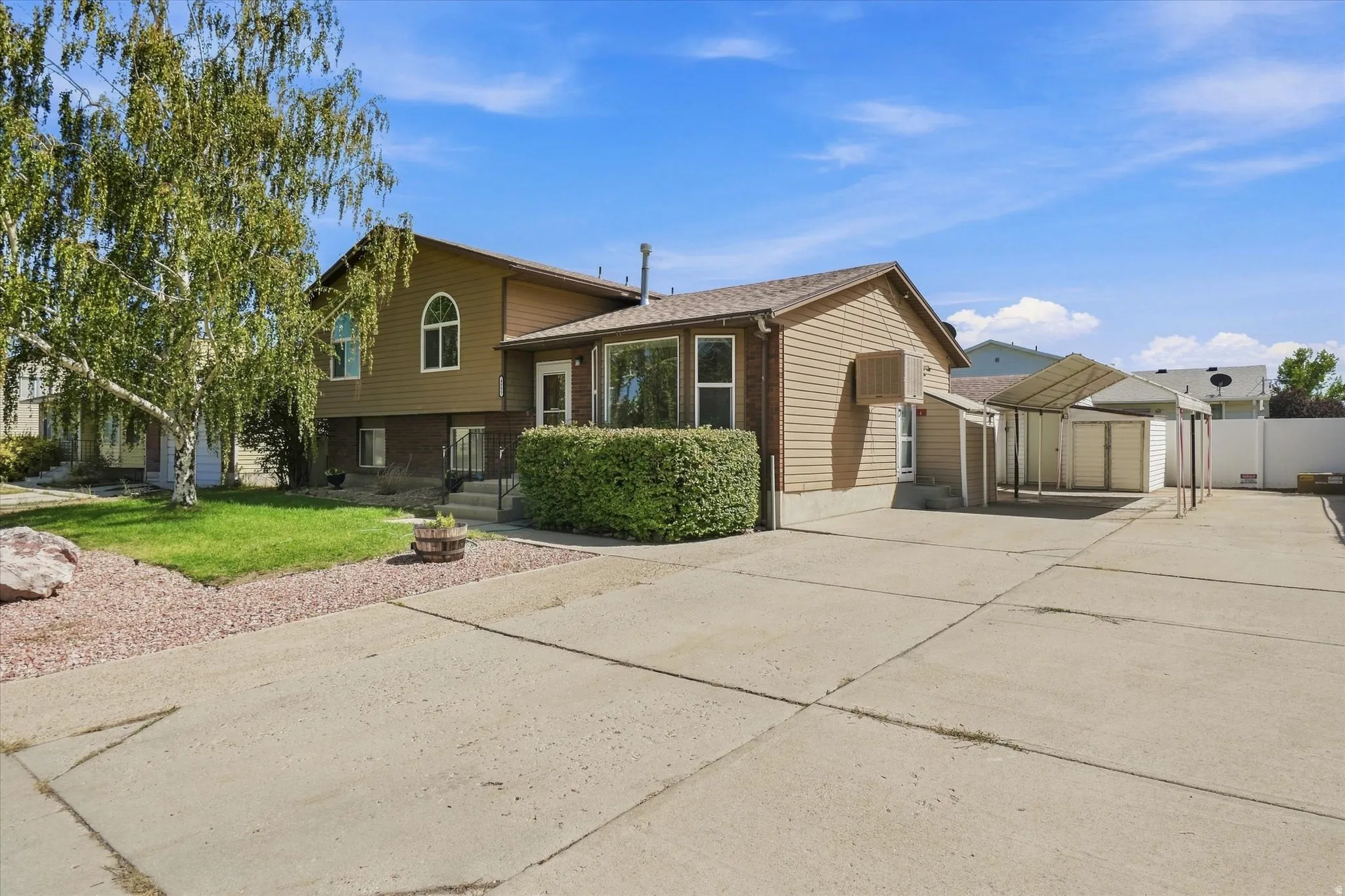 Expansive concrete driveway, carport, and shed provide ample utility