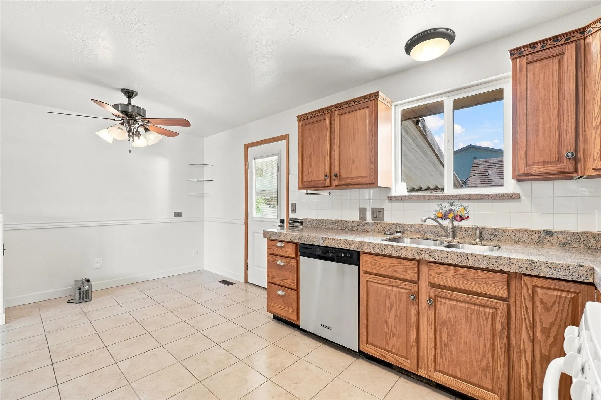Kitchen featuring wood cabinetry, laminate countertops, tile backsplash, stainless steel dishwasher, and tile flooring