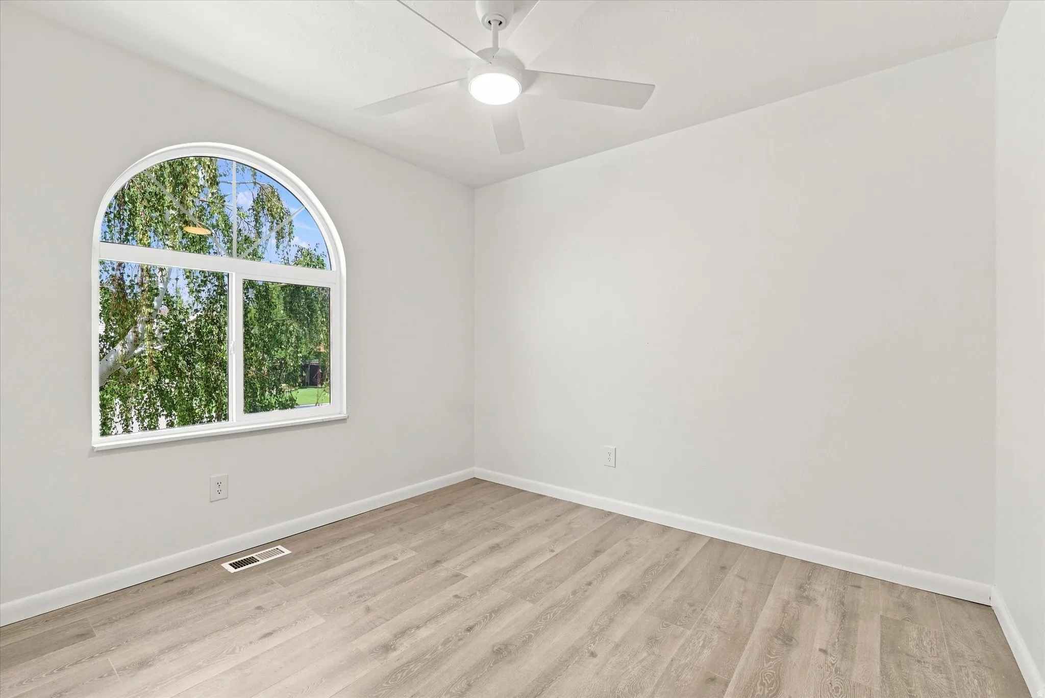 Arched window, wood-finish flooring, white walls, ceiling fan, recessed lighting