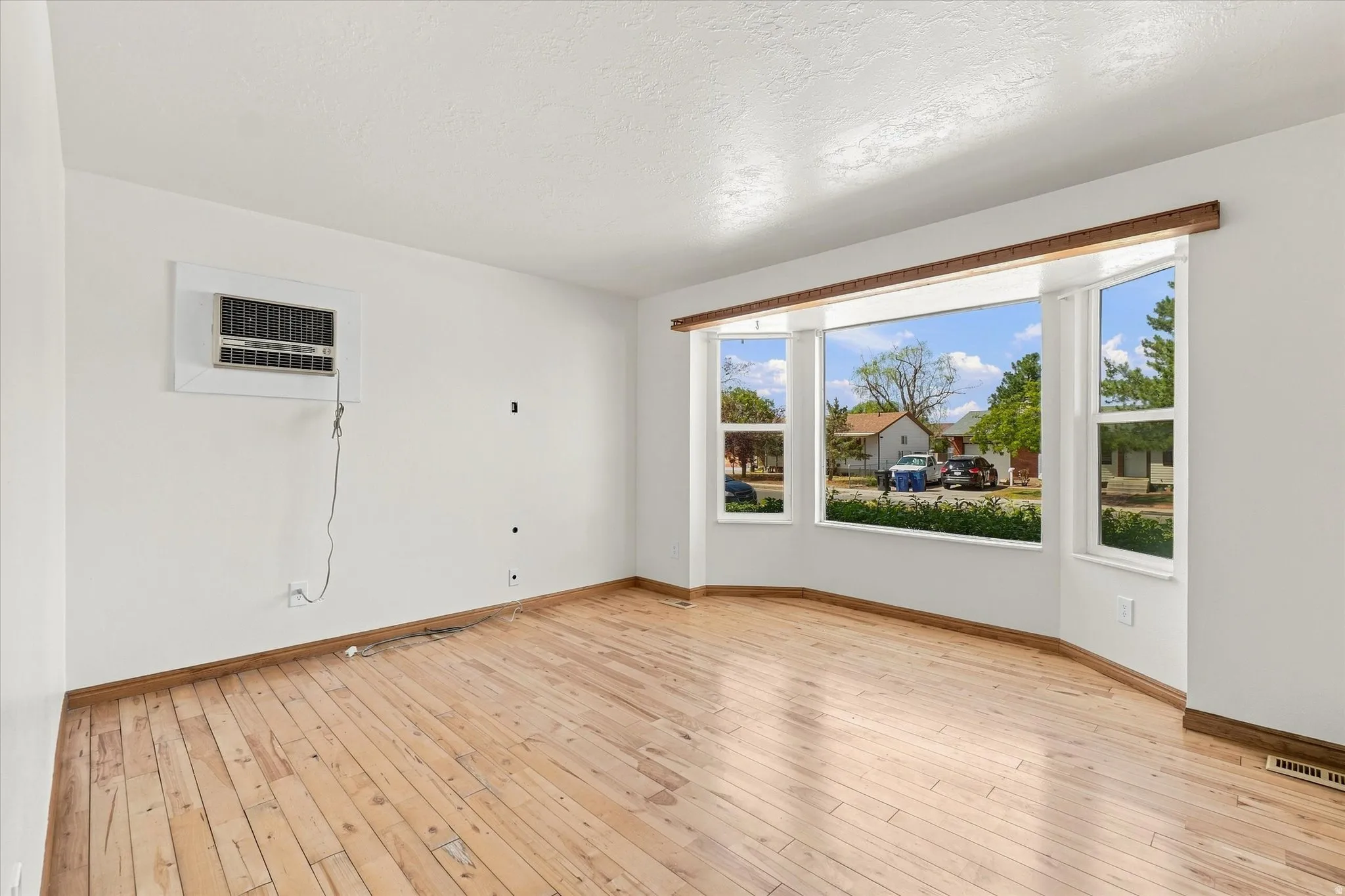 Bay window with multiple panes, wood-finish flooring, and white walls