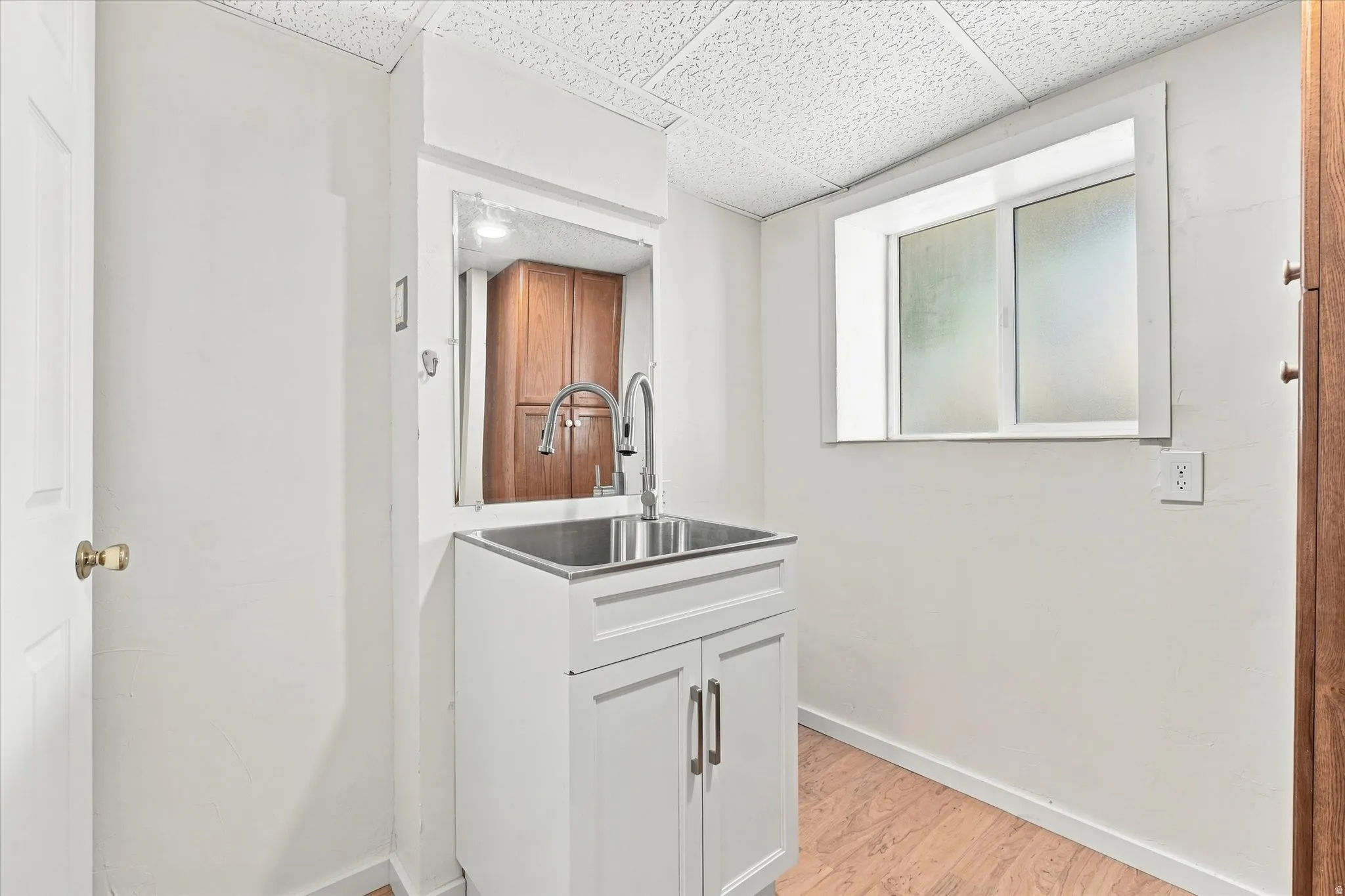 White shaker-style cabinetry with a stainless steel utility sink and modern faucet