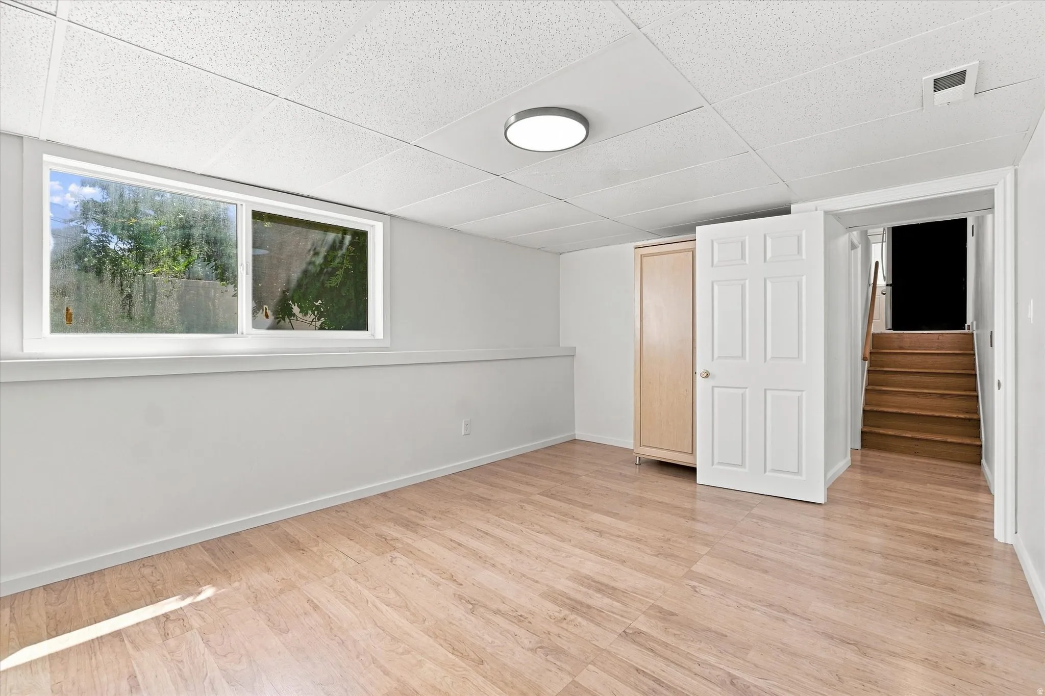 Wood-finish flooring, drop ceiling, and a flush-mount ceiling light