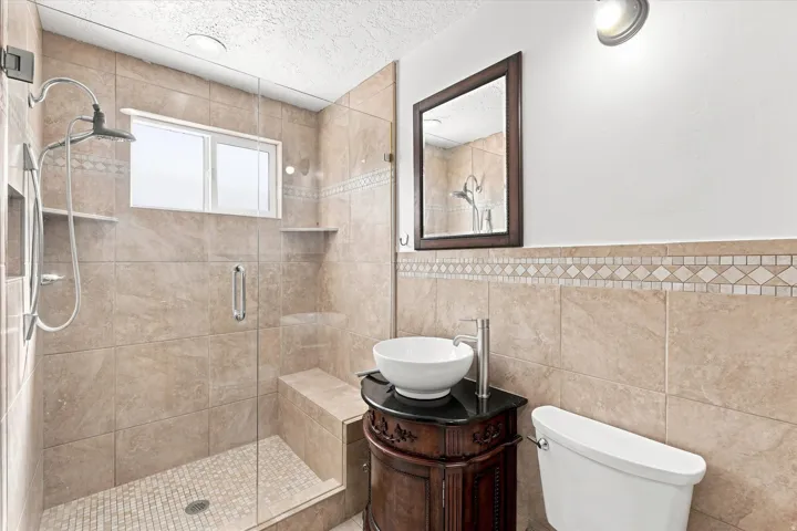 Tiled shower enclosure with a built-in bench, rain shower head, and an integrated niche