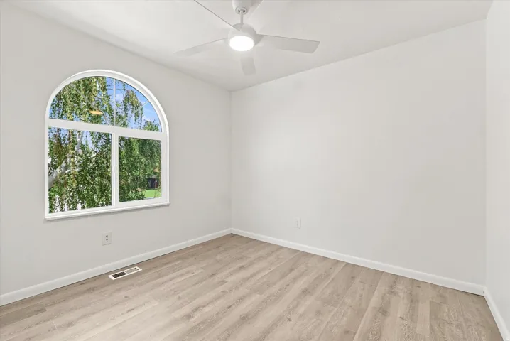 Arched window, wood-finish flooring, white walls, ceiling fan, recessed lighting