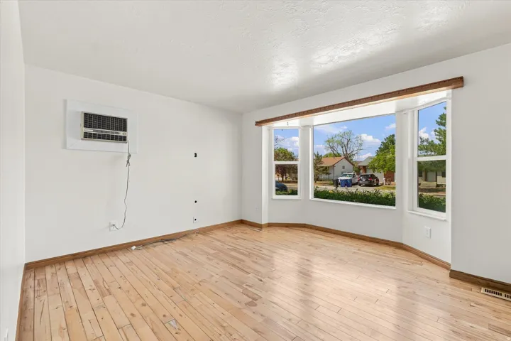 Bay window with multiple panes, wood-finish flooring, and white walls