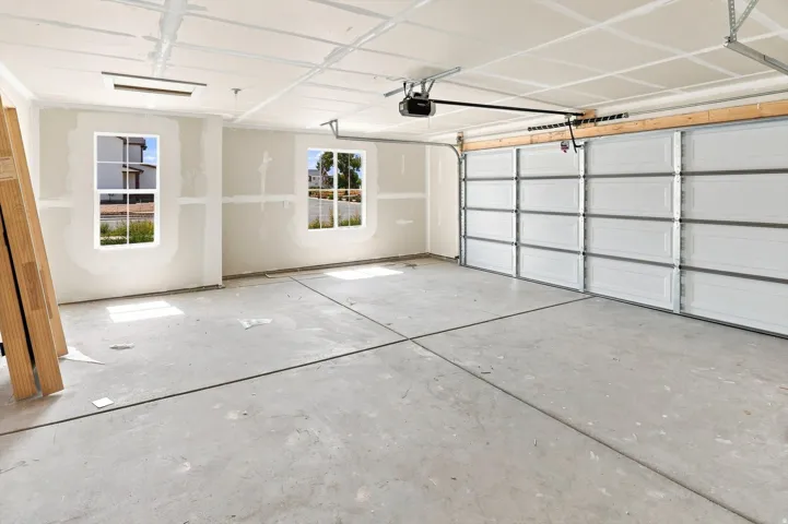 Spacious garage featuring a concrete floor, two windows, and an overhead garage door with an opener