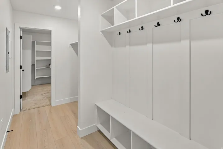 Built-in storage bench with cubbies, upper shelving, and black coat hooks
