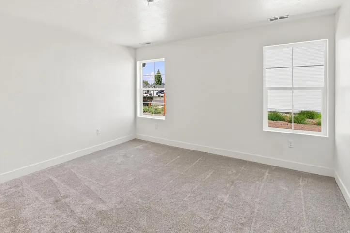Soft gray carpeting, two windows with white trim, and crisp white walls