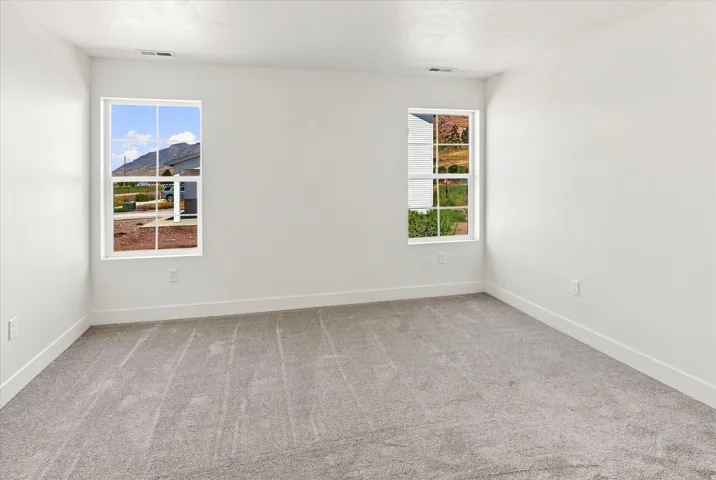 Light gray carpeted flooring, white painted walls, and two windows