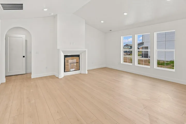 Spacious interior with wood-finish flooring, a recessed fireplace, and three large windows