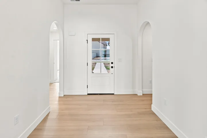 Entryway with light wood-finish flooring, white walls, and arched doorways