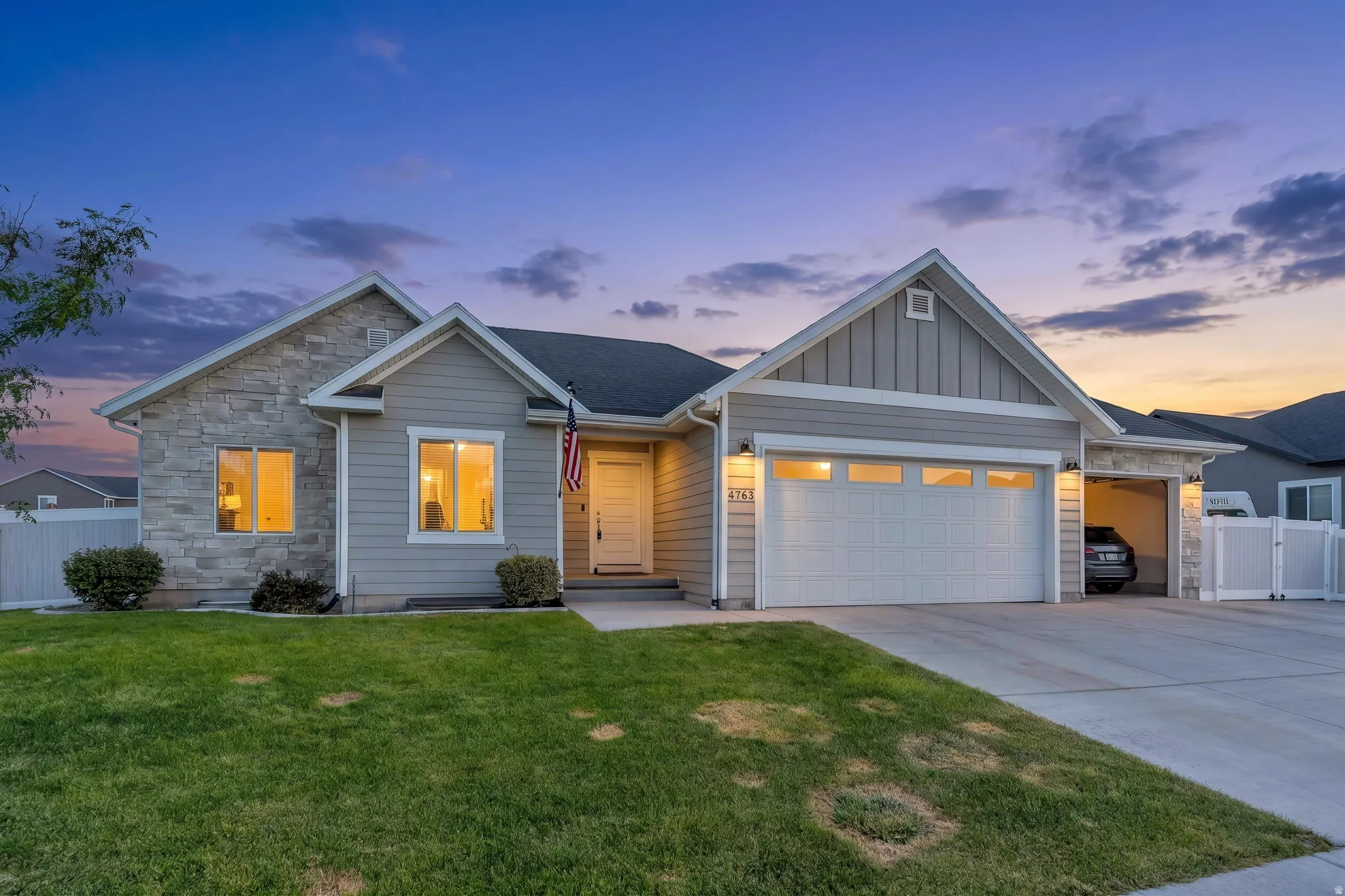 Stone and siding exterior with a two-car garage and additional covered parking