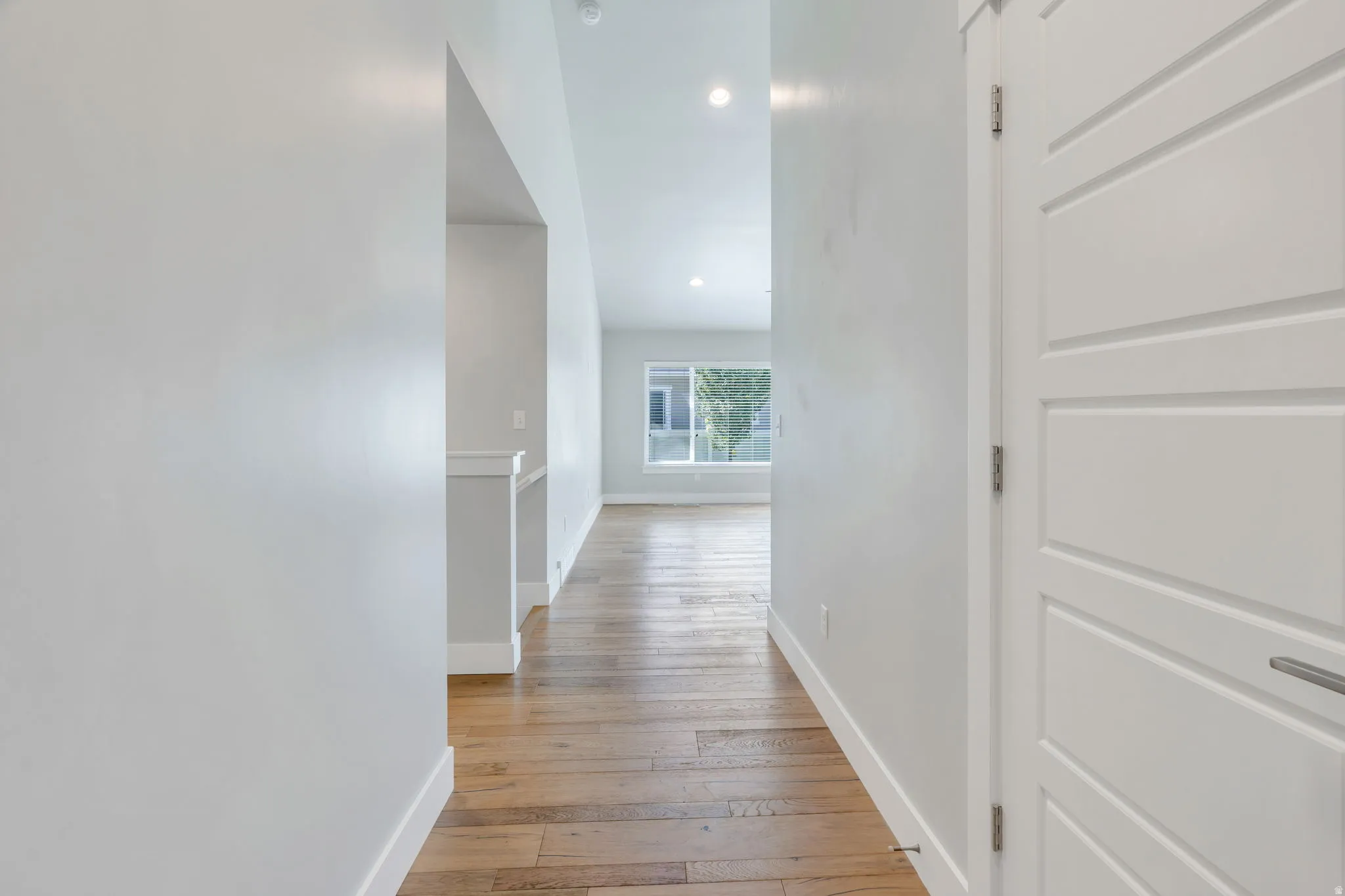 Hardwood flooring, recessed lighting, white interior doors with contemporary hardware, and a window providing natural light