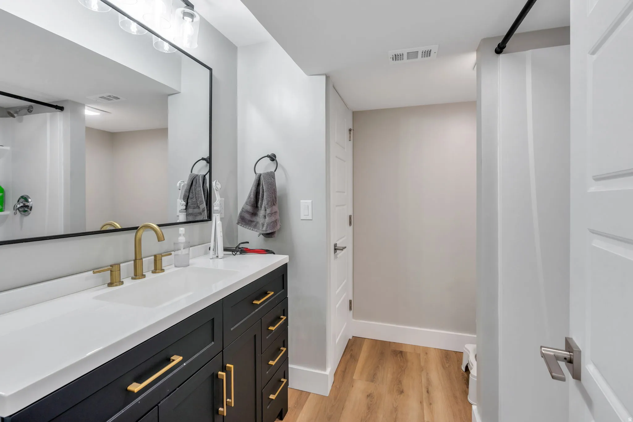Expansive vanity with a white countertop and brass-finish faucet