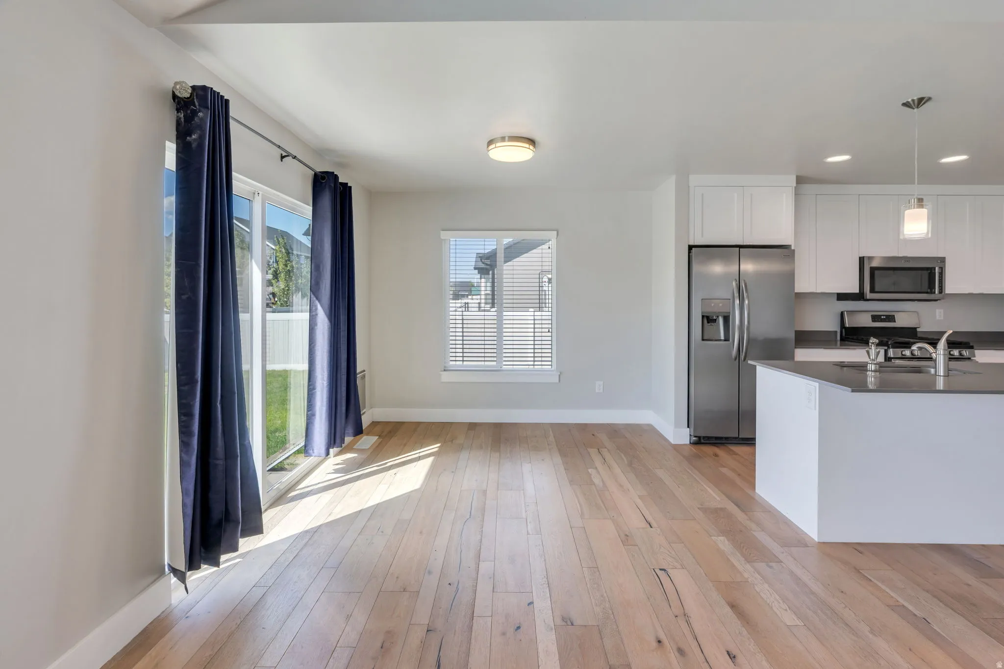 Open-concept living space featuring wood-finish flooring, a sliding glass door, and recessed lighting