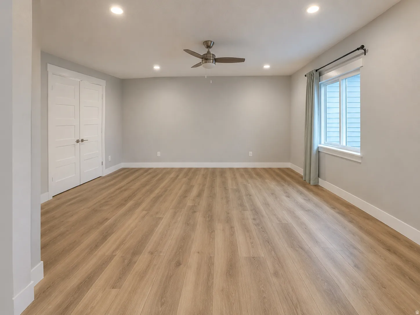 Expansive room featuring wood-finish flooring, recessed lighting, and a ceiling fan