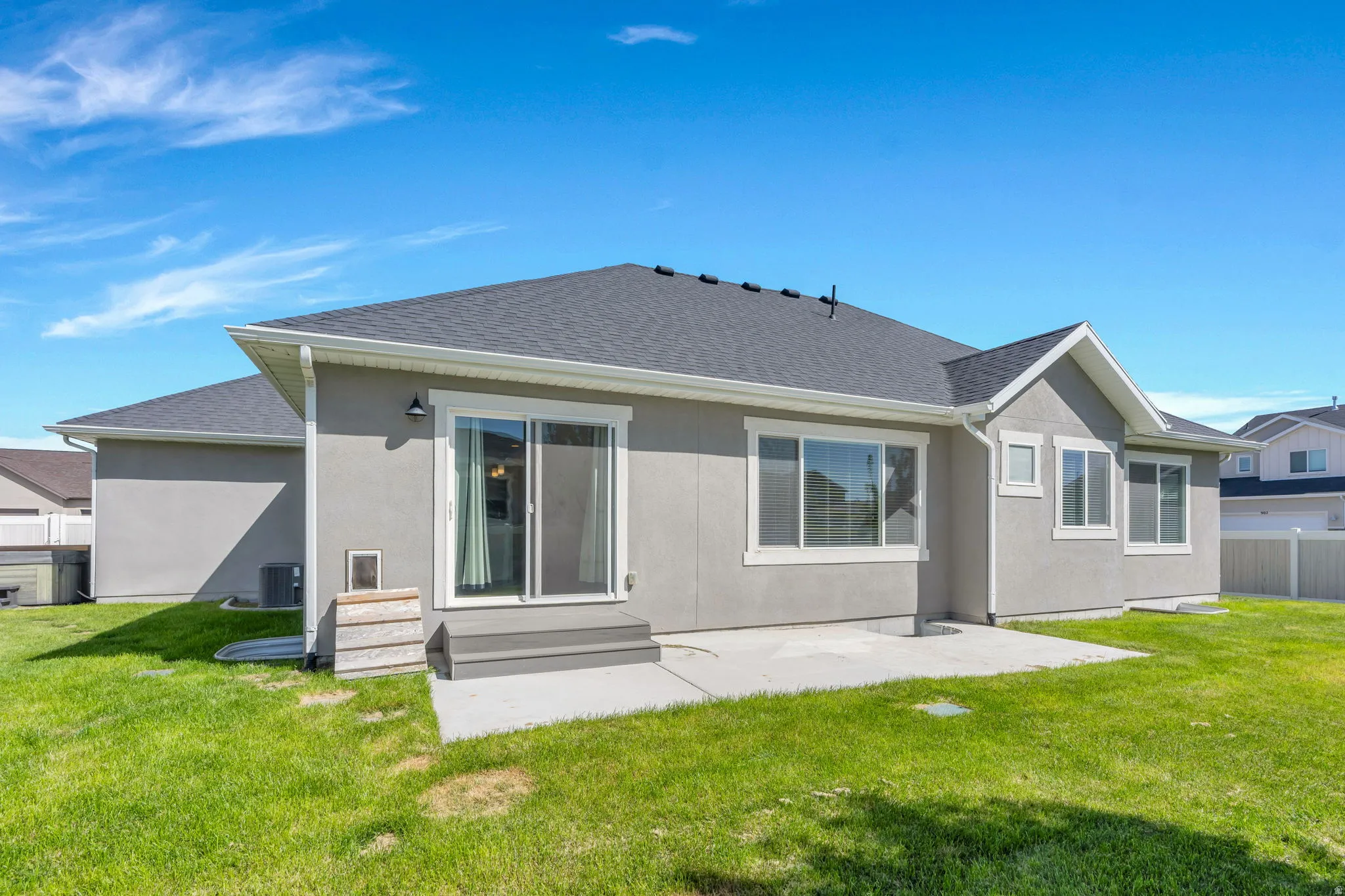 Expansive rear yard featuring a manicured lawn, concrete patio, and sliding glass door access