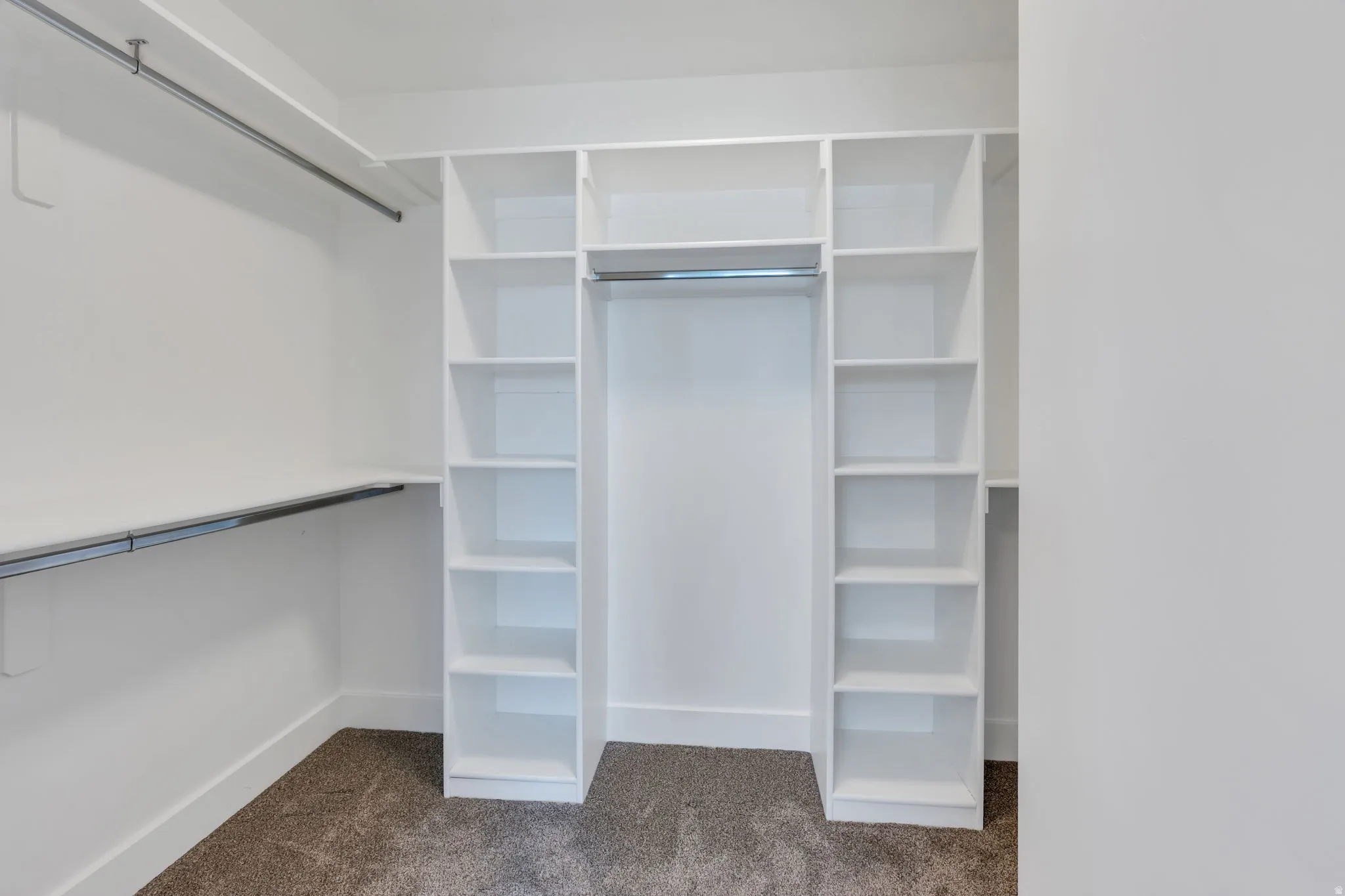 Built-in white shelving, integrated hanging rods, and carpeted flooring