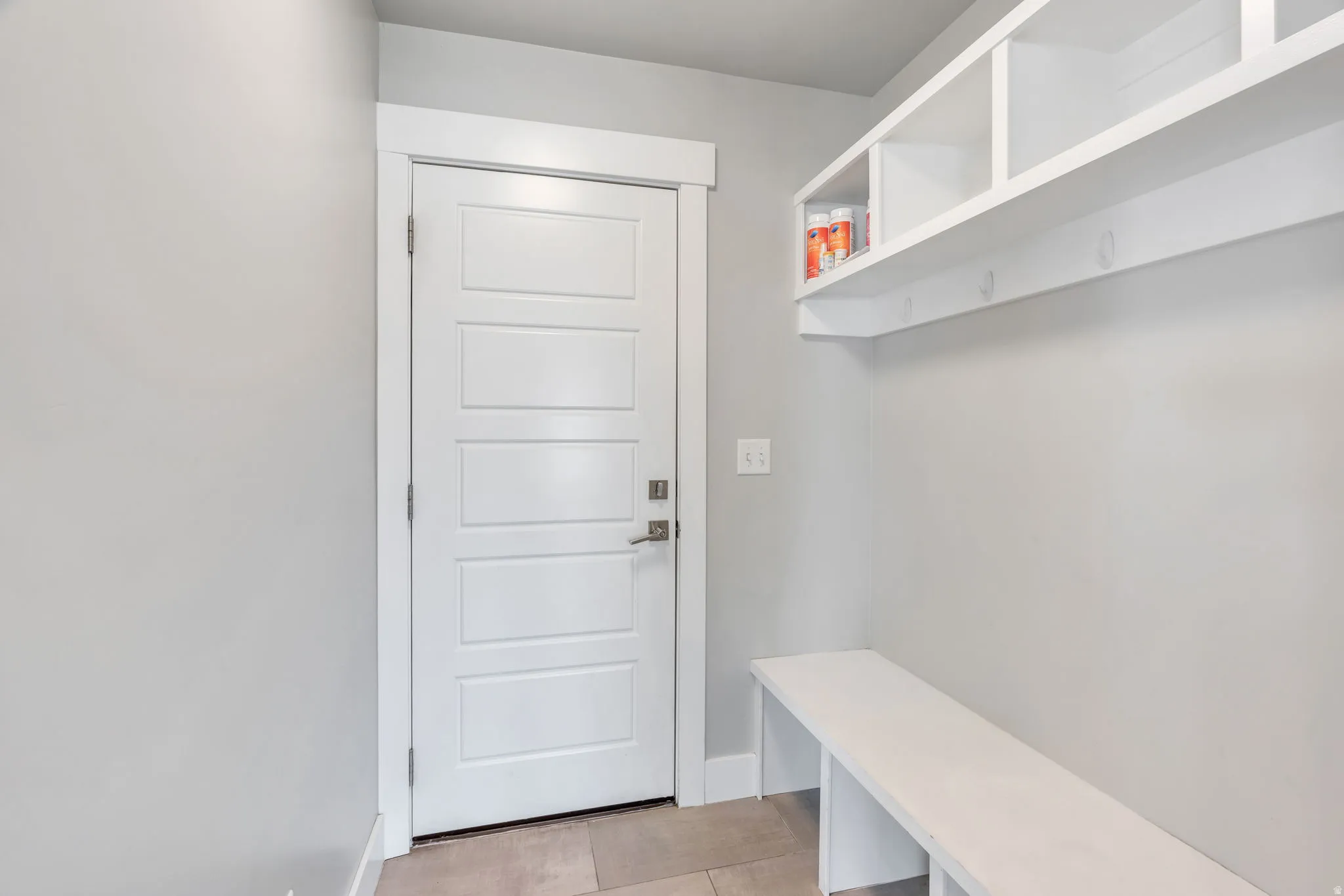 Built-in storage bench with open shelving, integrated coat hooks, and a paneled white door