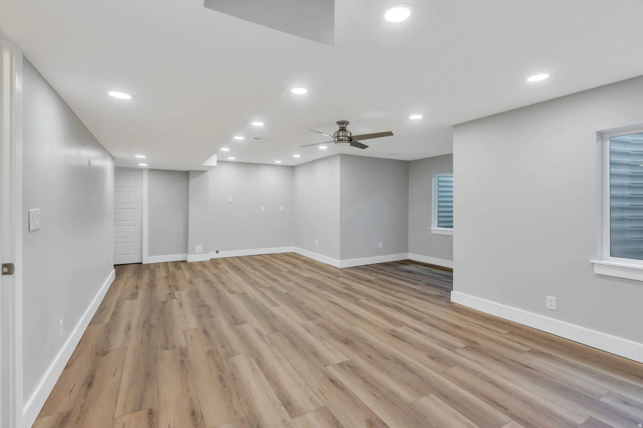 Spacious room featuring wood-finish flooring, recessed lighting, and a ceiling fan