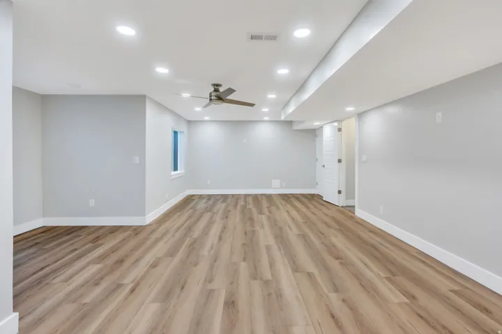 Spacious room featuring wood-finish flooring, recessed lighting, and a ceiling fan
