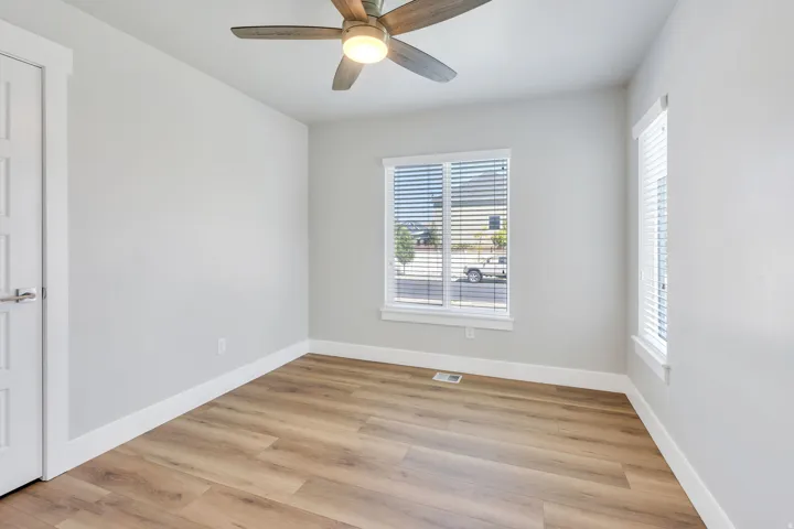 Wood-finish flooring, overhead lighting with a ceiling fan, and white window blinds
