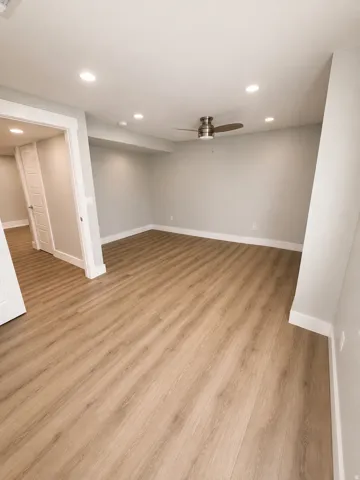 Wood-finish flooring with recessed lighting, a ceiling fan, and white trim
