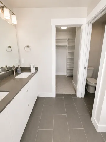Double vanity with undermount sinks, stone countertop, and contemporary light fixture