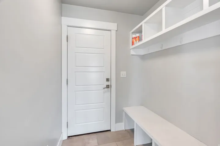 Built-in storage bench with open shelving, integrated coat hooks, and a paneled white door