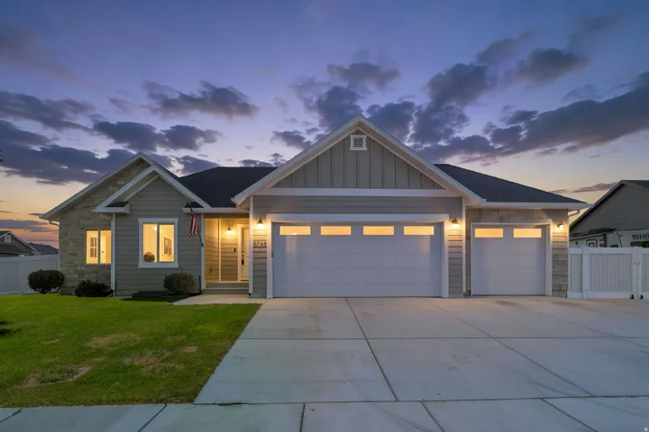 Modern ranch-style exterior featuring stone and siding finishes, an attached three-car garage, and a concrete driveway