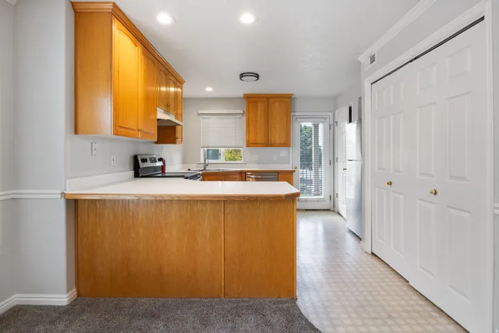 Kitchen featuring wood cabinetry, white countertops, stainless steel appliances, and patterned flooring