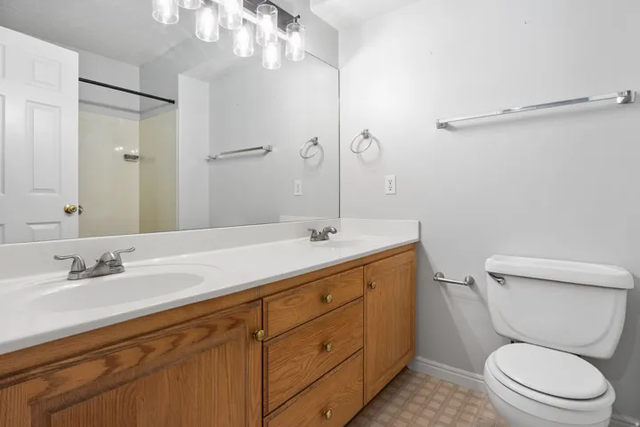 Dual vanity with laminate countertops, wood cabinetry, and a full-width mirror