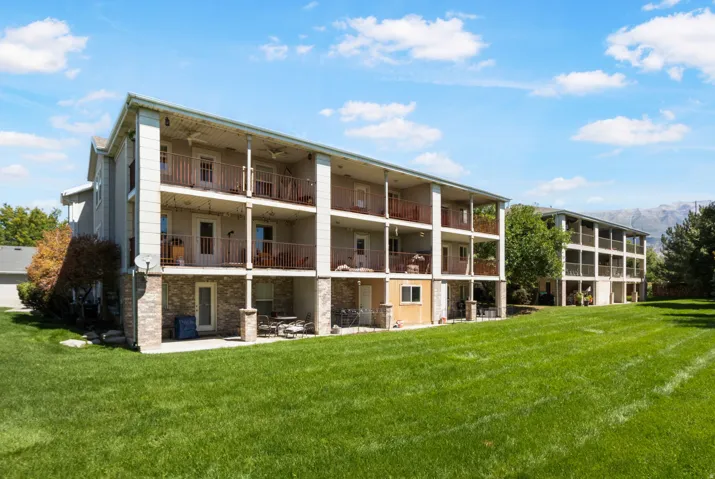 Multi-story building featuring multiple private balconies, ground-level patio spaces, and brick-finish foundation