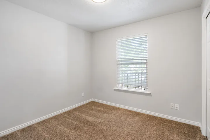 Neutral tone wall finish with a single window featuring horizontal blinds