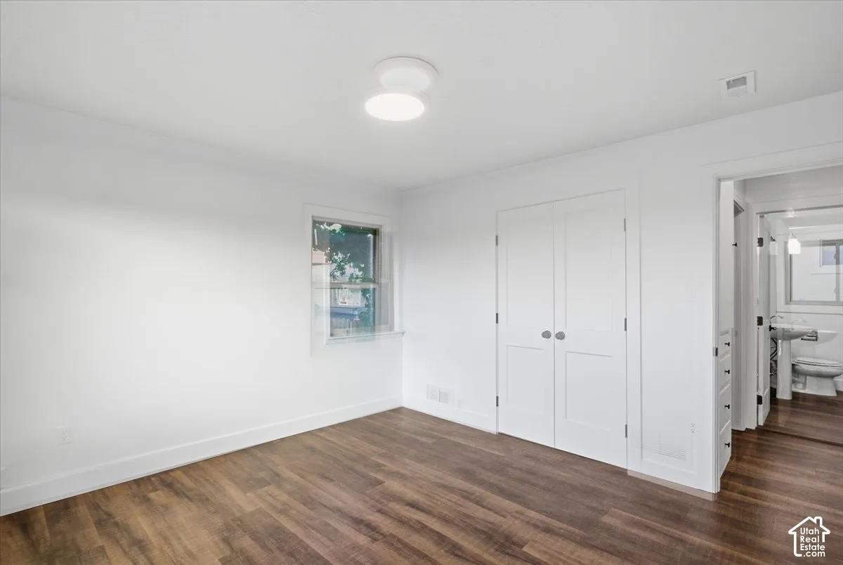 Wood-finish flooring throughout, bright white walls, built-in closet with double doors, and a ceiling-mounted light fixture