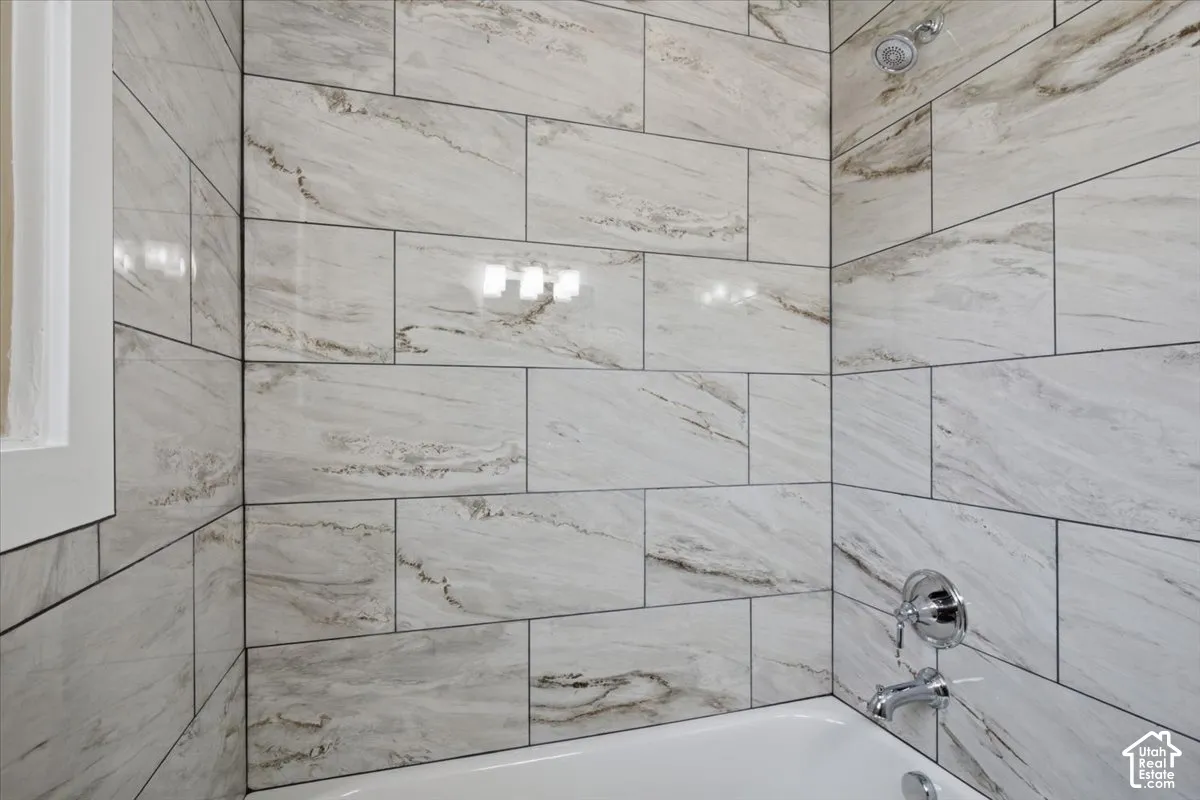 White subway tile shower surround with contrasting dark grout, chrome showerhead, and tub filler