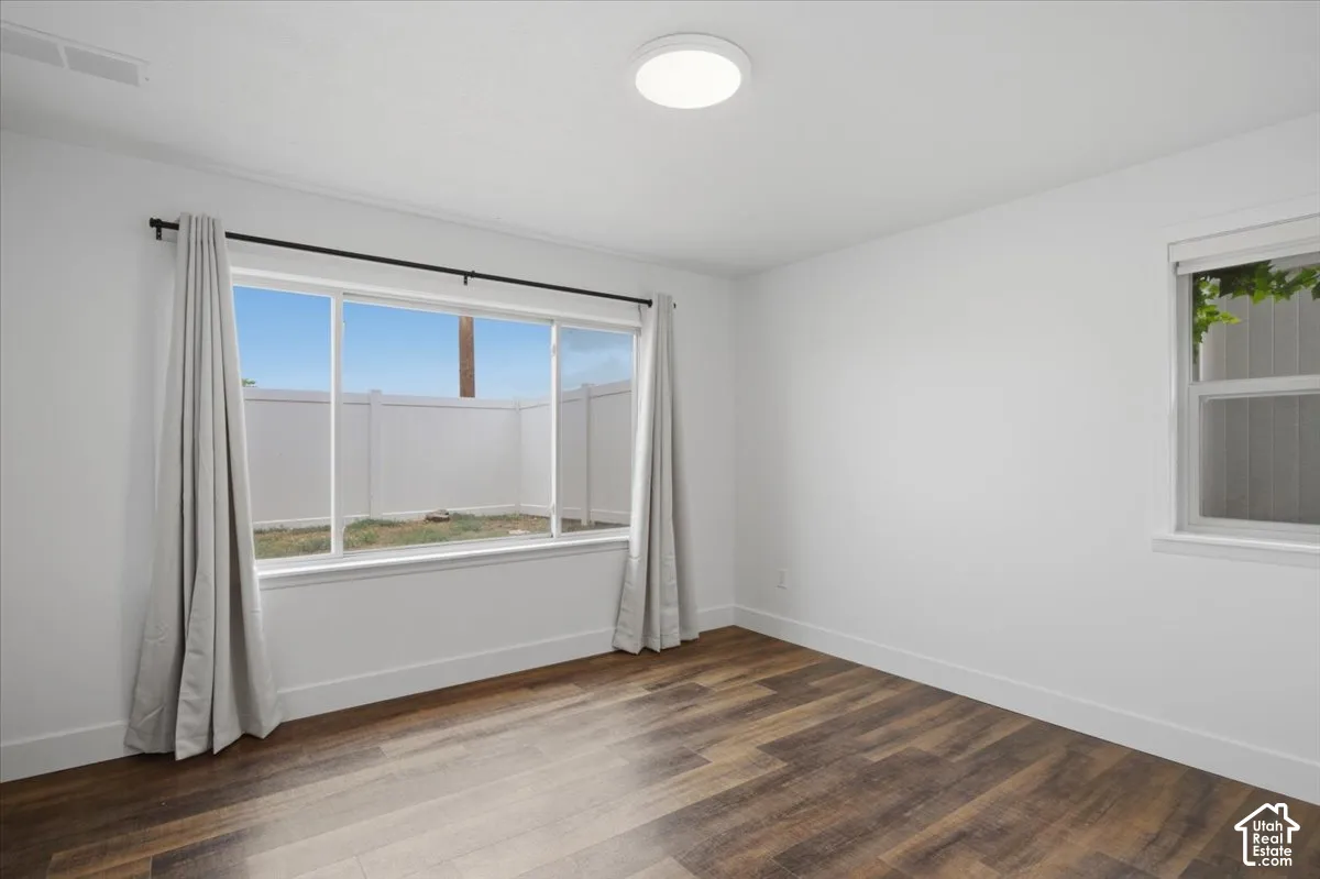 Wood-finish flooring, white walls, two windows, and a flush-mount ceiling light