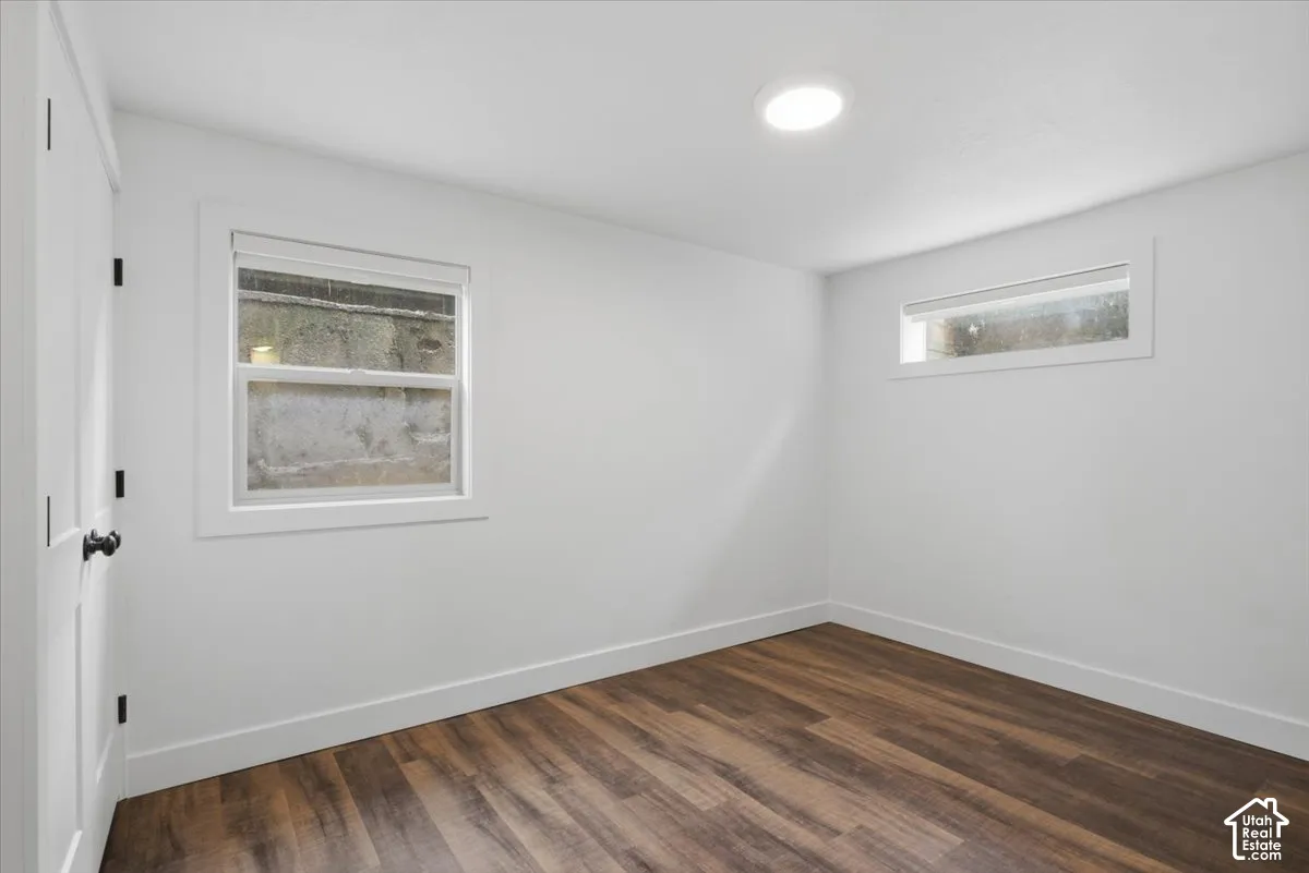 Recessed ceiling lighting, wood-finish flooring, white trim, and a white interior door with black hardware
