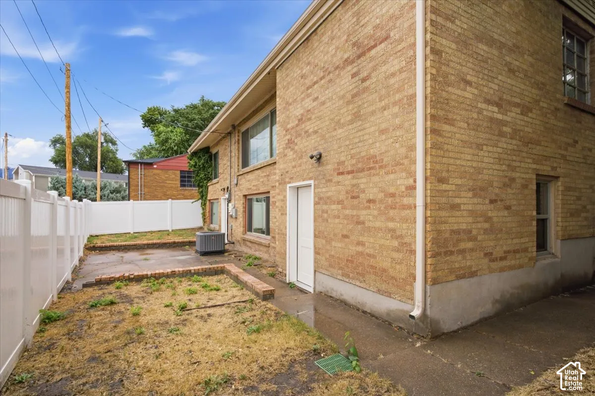 Brick exterior with multiple windows, white privacy fencing, and a concrete pathway