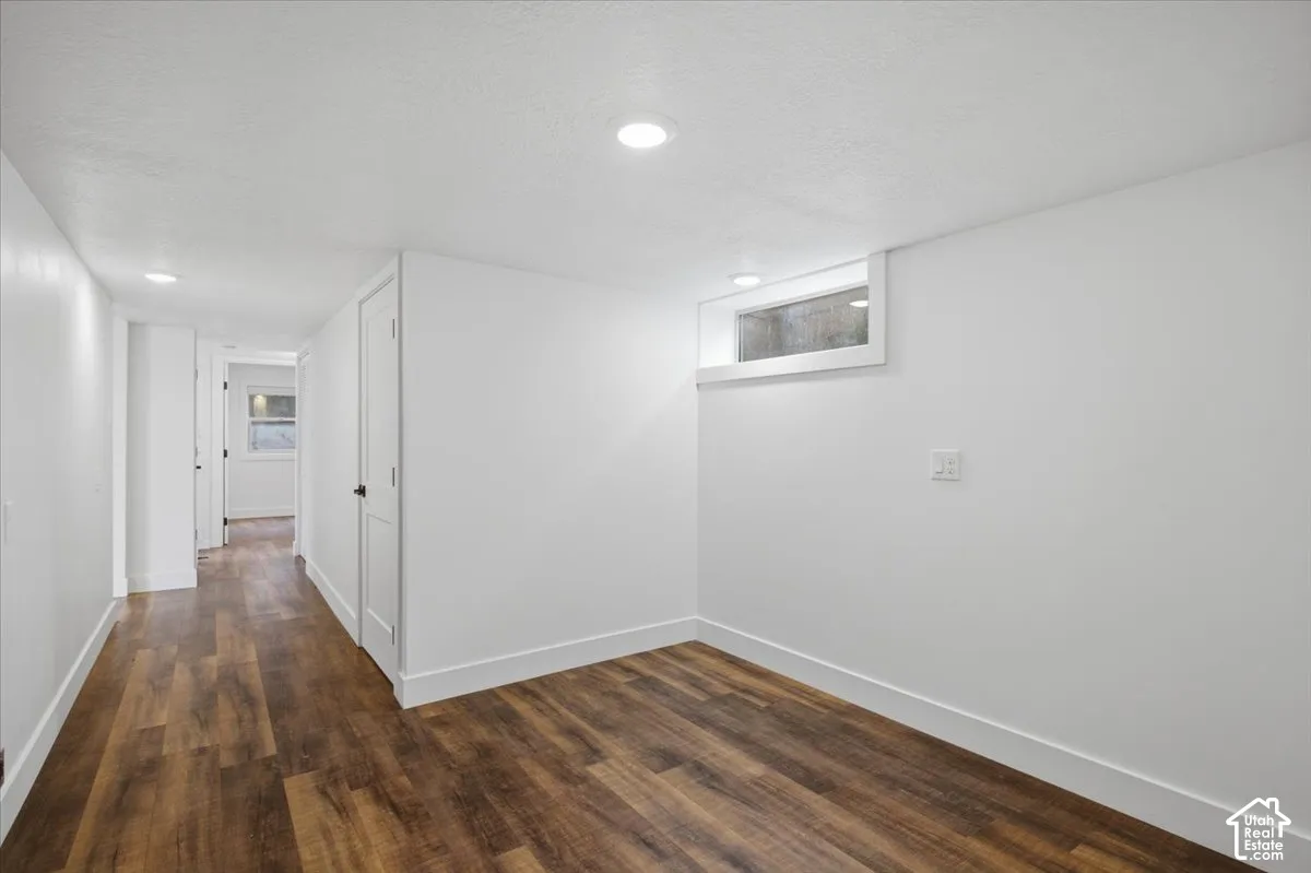 Recessed lighting, wood-finish flooring, white paneled doors, and a window well provide illumination